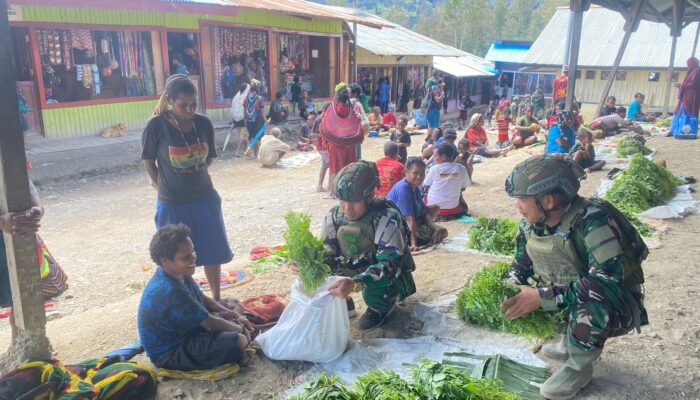 Personil Pos Sinak Satgas Yonif 700/WYC Belanja Hasil Tani Masyarakat di Pasar Sinak mama Papua tersenyum Bahagia